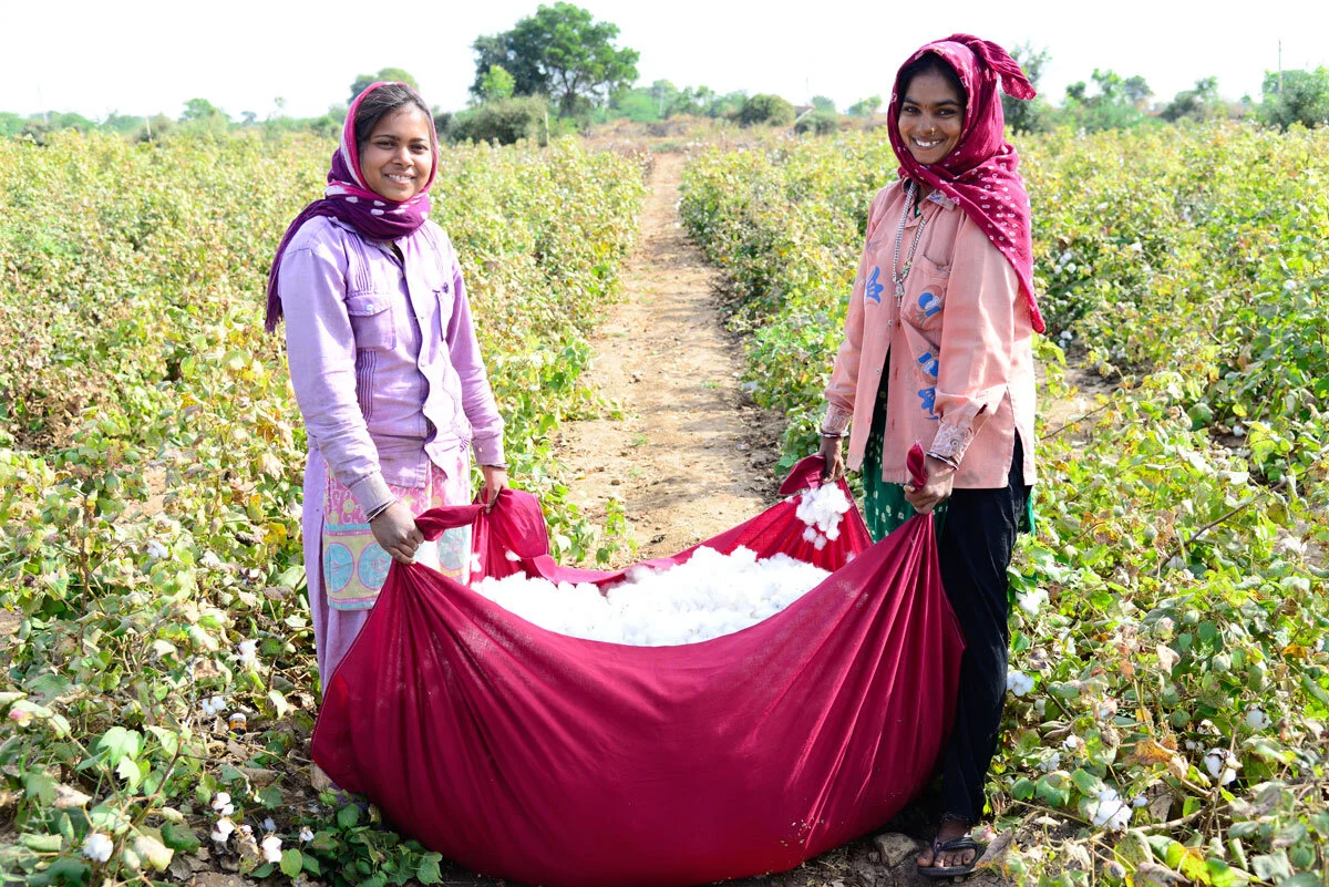 Two ladies holding a sheet of material containing cotton